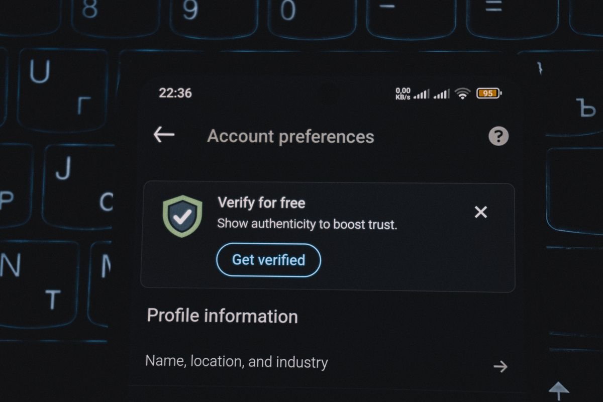 A smartphone screen displays an account verification alert, held in someone's hand