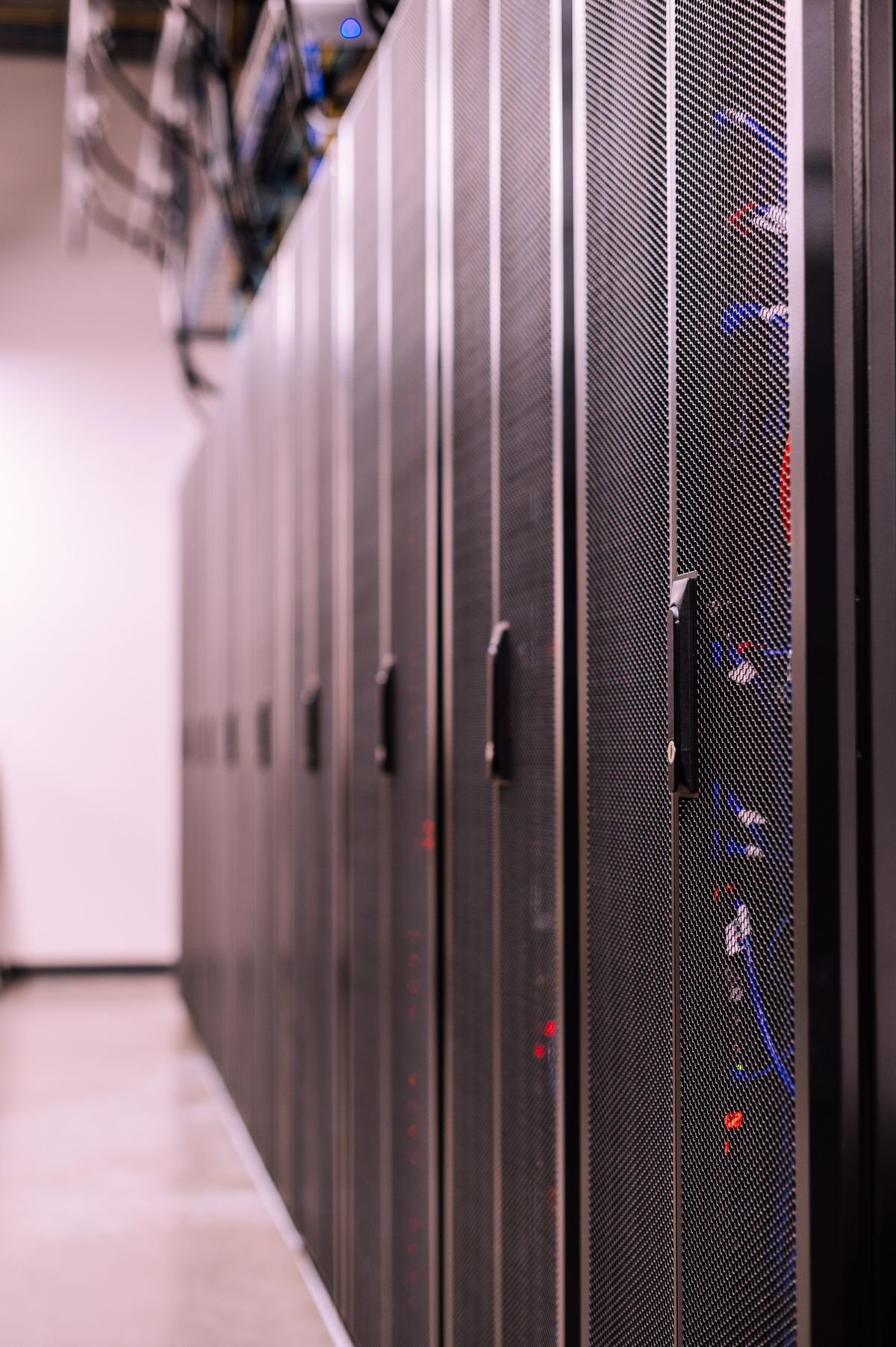 A row of server cabinets with fibre optic cables in a data server room
