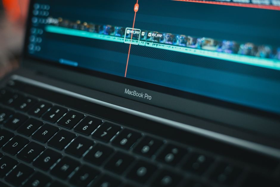 MacBook screen showing a video editing timeline with waveform and caption tracks, the kind of setup used to add auto-generated subtitles to short-form video